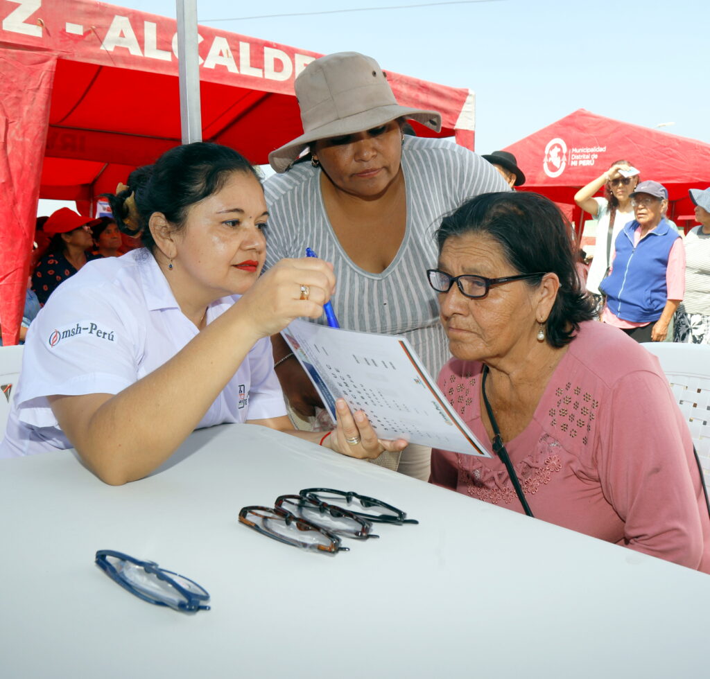 A staff member helps an older woman during a vision screening event.