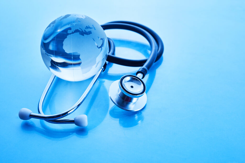 A stethoscope wrapped around a glass globe on blue background