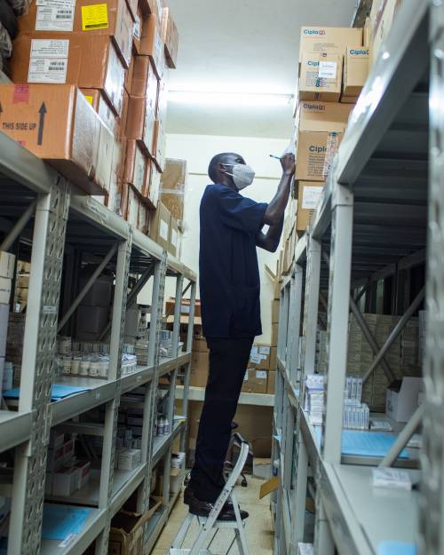A healthcare worker checks and records medicine inventory.