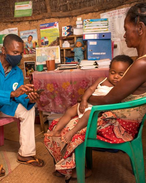 A community health worker records patient information during a home visit