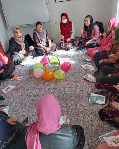Women in Afghanistan gather around for a group antenatal care activities involving color balloons.