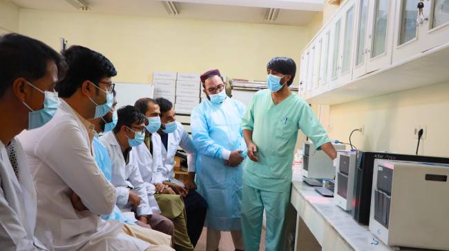 A group of lab technicians observing a GeneXpert machine.